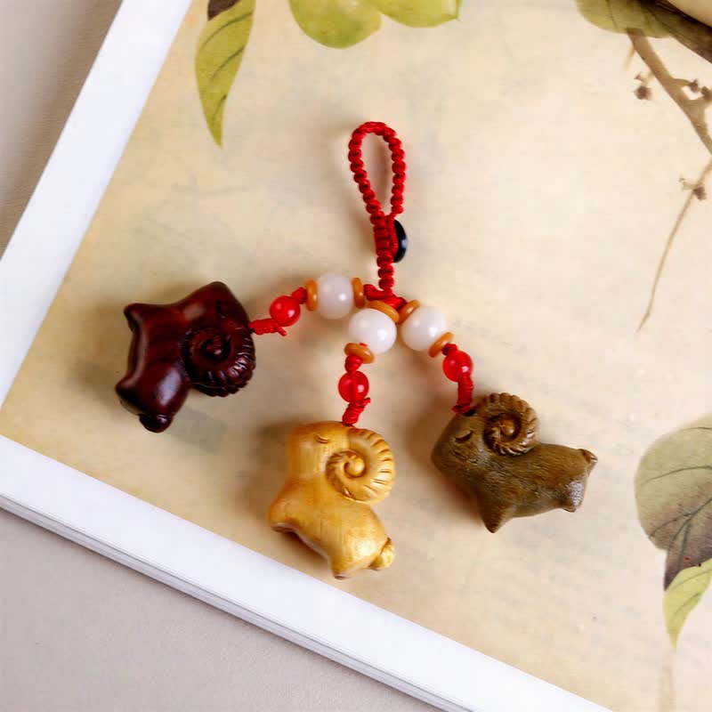 Buddha Stones Handgeschnitzte Schlüsselanhänger aus Sandelholz und Ebenholz mit drei Ziegen als Symbol des Wohlstands - image 1